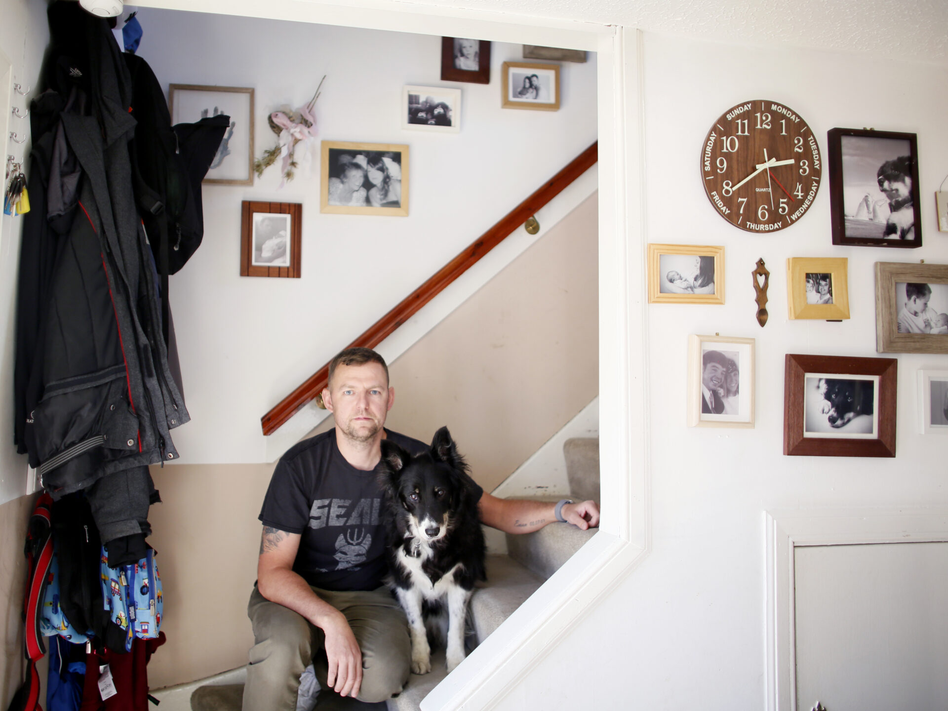 Former refinery control room operator James Differ sitting on stairs at home with his dog beside him.